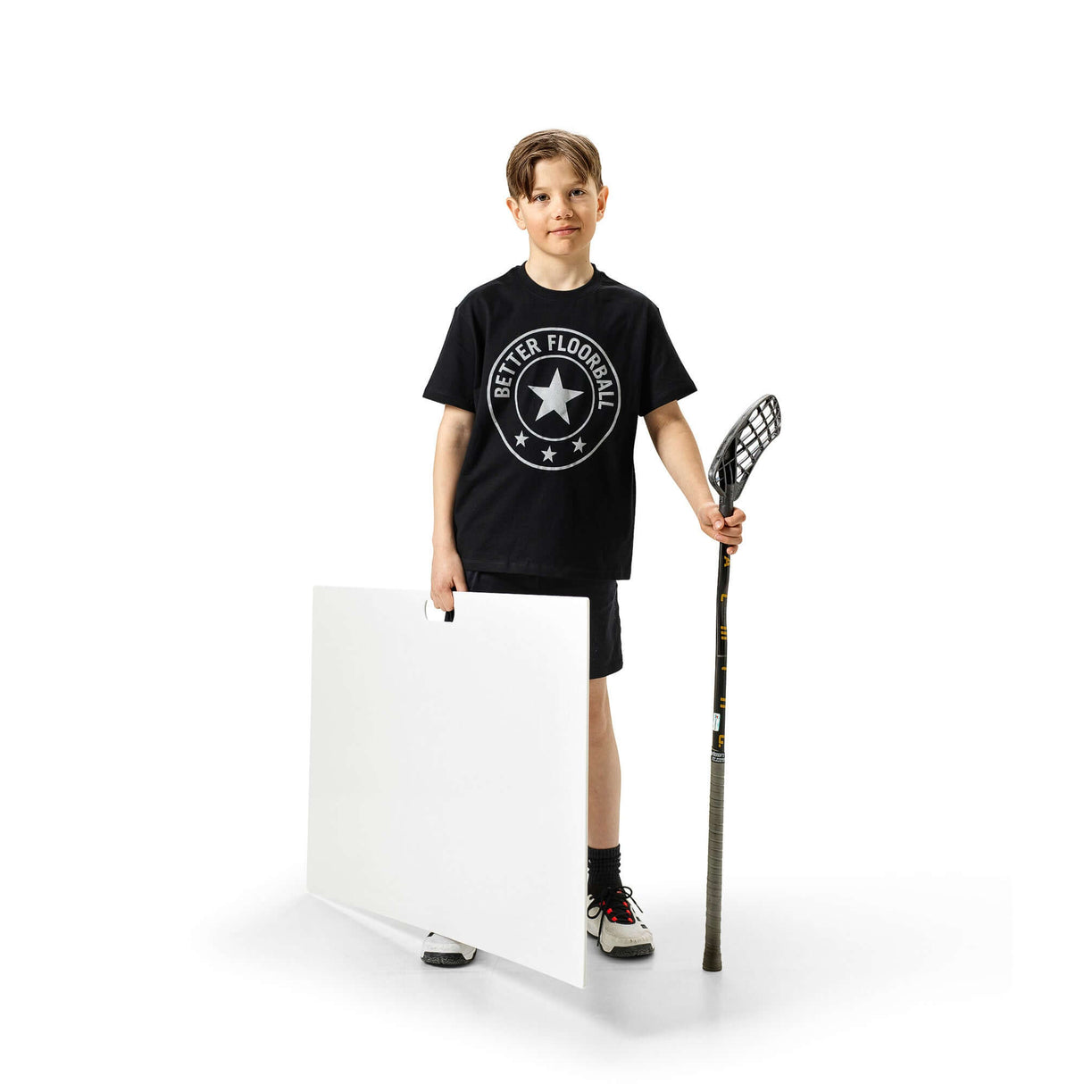 Ung kille med skottramp innebandy och klubba i handen, redo för träning.